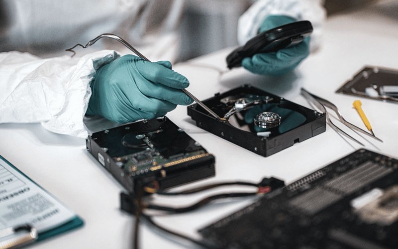 Forensic examiner in gloves inspecting an opened hard drive